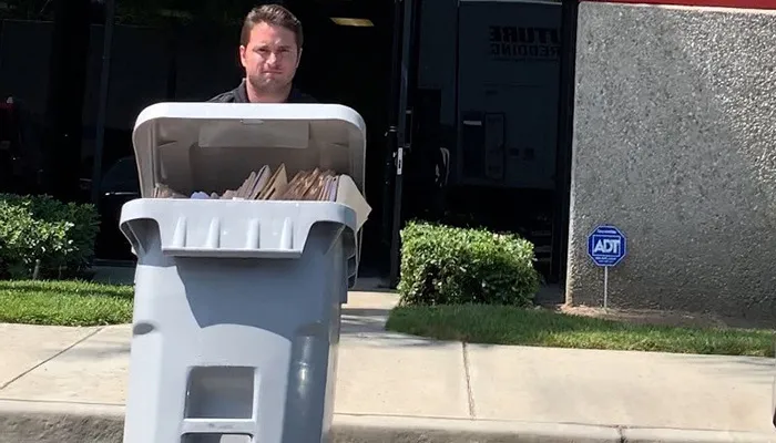 Future Shredding team member wheeling a full locked shred bin to the truck